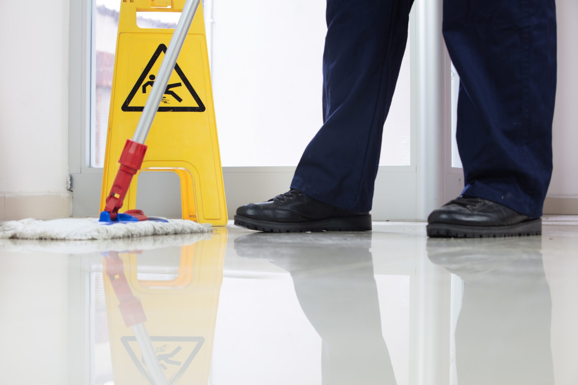 low-angle-closeup-person-cleaning-floor-with-mop-near-yellow-caution-wet-floor-sign_freepik-18-02-2022